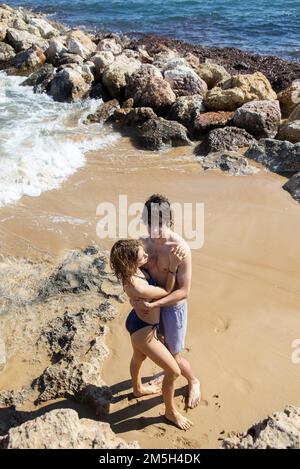 young man and woman about 20 years old, a couple in love, in full growth gently hugging on the beach. enjoyment of the moment, tender feelings, pleasa Stock Photo
