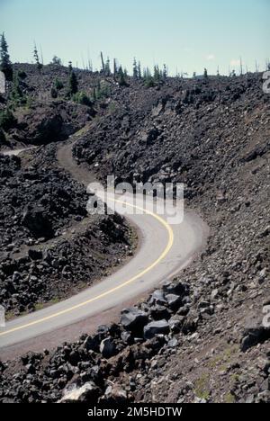McKenzie Pass-Santiam Pass Scenic Byway - Winding Through Lava on McKenzie Pass - Santiam Pass Scenic Byway. A two-lane road curves around tall hills of lava rocks. Location: Oregon (44.260° N 121.798° W) Stock Photo