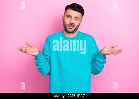 Photo of young funny grimace guy wear blue sweatshirt shrug shoulders dont know where money stolen cant help you isolated on pink color background Stock Photo