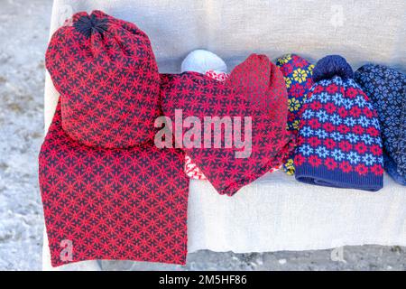 Winter hat and mittens knitted with jacquard on a white background. View from the top. Lying flat. Christmas craft market. Stock Photo