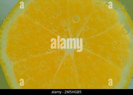 Fresh lemon slice in liquid with bubbles. Close-up of a lemon slice in soda water. Bubbles on lemon. Slice of lemon in carbonated water Stock Photo