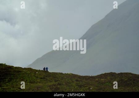 Two trekkers brave rainy spring weather on a trail in the Red Cullins on the Isles of Skye, Scotland, UK Stock Photo