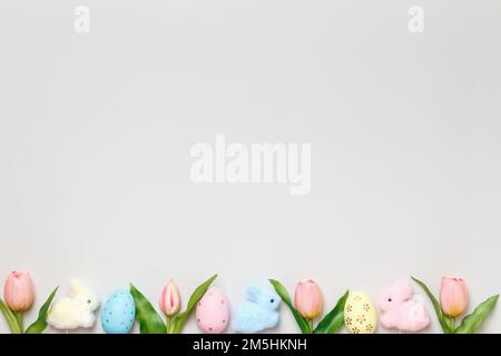 Easter banner border. Eggs of tulips of toy rabbits on a gray background. Stock Photo
