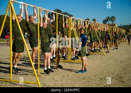 U.S. Marine Corps recruits with Kilo Company, 3rd Recruit Training Battalion, perform pullups during a strength and endurance course at Marine Corps Recruit Depot San Diego, March 18, 2022. Exercises such as squats, lunges, crunches, pull ups, dips and a two-and-a-half-mile run are meant to help recruits develop some of the skills needed by all Marines in combat environments. Stock Photo