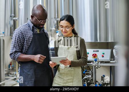 Couple of engineers using tablet pc to watch process of production materials online , they working in team Stock Photo