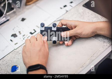 In the electronics repair shop, the master repairs, cleans, controls, arranges the smartphone. Uses equipment and tools for work. Workplace top view, Stock Photo