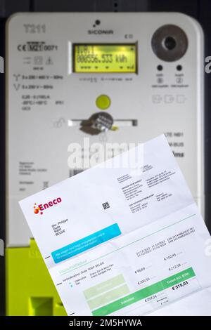 Invoice from Eneco, Belgian producer and supplier of natural gas and electricity in front of Fluvius smart meter in house in Belgium Stock Photo