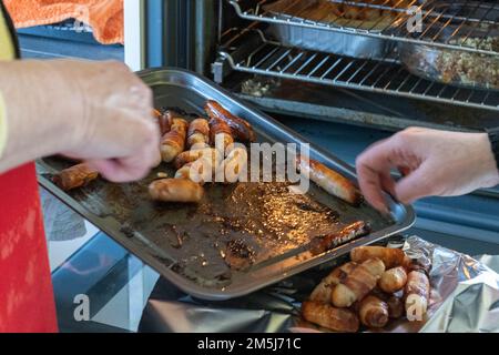 Pigs in blankets ( sausage wrapped in bacon) being removed after being cooked in electric oven Stock Photo