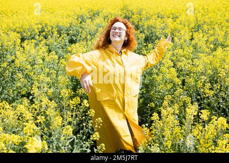 A woman enjoying and dancing in a beautiful yellow field Stock Photo