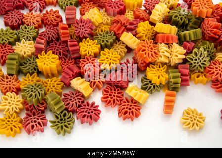 Edelweiss flower shaped egg pasta typical of the Langhe; Italy. Colorful dough pasta with spinach, carrot and beetroot, macaroni isolated on white in Stock Photo