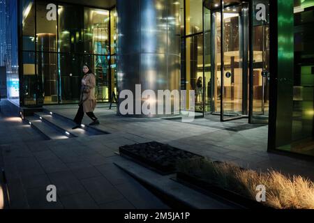 Woman walks out of the Federation Tower in Moscow International Business Centre (MIBC) at night. Moscow, Russia. Stock Photo