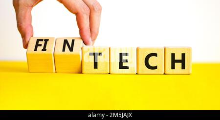 Tech or fintech symbol. Concept word Tech and Fintech on wooden cubes. Businessman hand. Beautiful yellow table white background. Business and tech or Stock Photo