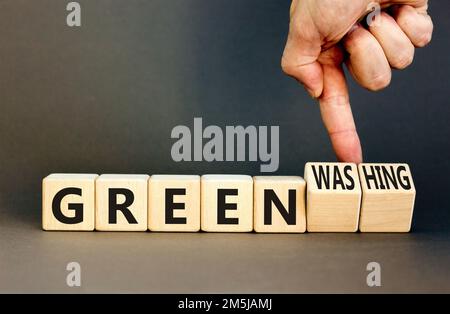 Green or greenwashing symbol. Concept words Green and Greenwashing on wooden cubes. Businessman hand. Beautiful grey table grey background. Business g Stock Photo