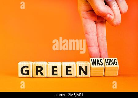 Green or greenwashing symbol. Concept words Green and Greenwashing on wooden cubes. Businessman hand. Beautiful orange table orange background. Busine Stock Photo