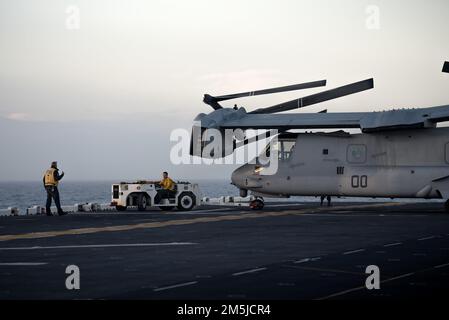 ATLANTIC OCEAN – Aviation Boatswain's Mate (Handling) 3rd Class Andrew Gabris operates ground supportive equipment to maneuver a MV-22 Osprey assigned to Marine Medium Tiltrotor Squadron (VMM) 263, across the flight deck of the Wasp-class amphibious assault ship USS Kearsarge (LHD 3) during Fleet Battle Problem 22-1, March 19, 2022. FBP 22-1 integrates naval capabilities to support special operations, provide defense ashore and at sea, and develop the use of unmanned underwater vehicles. Stock Photo