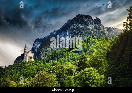 Neuschwanstein Castle stands out against the forest and mountains in Bavaria, Germany. Stock Photo