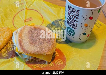 Paper cup of Ethically sourced coffee and Egg McMuffin on a yellow wrapper. Stock Photo