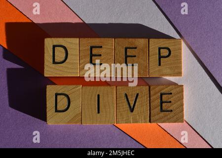Deep Dive, business buzzword meaning to discover the root cause of a problem to identify the solution, in wooden alphabet letters isolated on backgrou Stock Photo