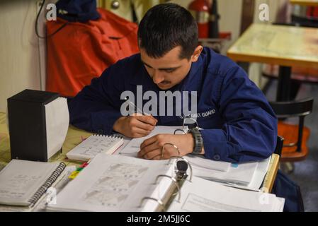 U.S. Coast Guard Seaman Alexander Landry, aboard to Coast Guard Cutter Spar, studies for his qualifications on the mess deck while underway in the Atlantic Ocean, March 19, 2022. Spar and her crew are traveling to Duluth, Minn. after a year-long maintenance period in Baltimore. Stock Photo