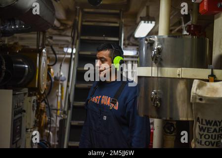U.S. Coast Guard Petty Officer 3rd Class Adolfo Hernandez, a Machinery Technician aboard Coast Guard Cutter Spar, conducts an hourly round of the engine room while underway in the Atlantic Ocean, March 19, 2022. Spar and her crew are traveling to Duluth, Minn. after a year-long maintenance period in Baltimore. Stock Photo