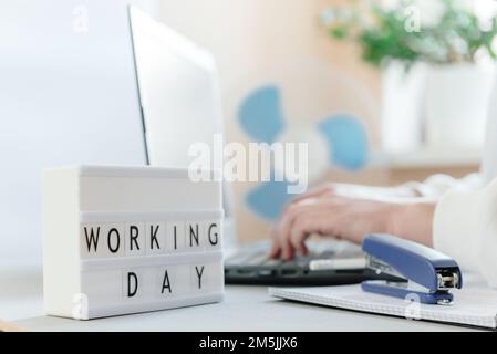 Workplace with a laptop, hands of a man, notepad on a white background. Freelancer's workplace. Workday text inscription and blank space for text Stock Photo