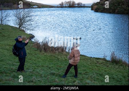 Thursday December 29th 2022: Edinburgh Scotland, UK. Tourists take photos in Holyrood Park beside Dunsapie Loch. Stock Photo