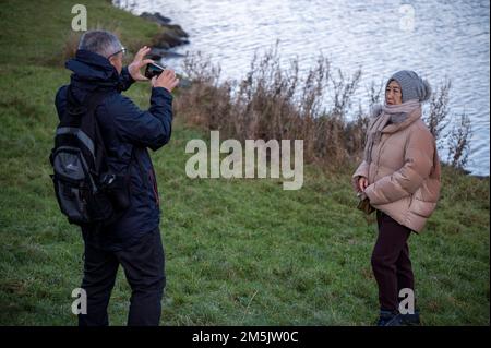 Thursday December 29th 2022: Edinburgh Scotland, UK. Tourists take photos in Holyrood Park beside Dunsapie Loch. Stock Photo