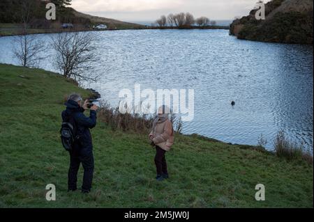 Thursday December 29th 2022: Edinburgh Scotland, UK. Tourists take photos in Holyrood Park beside Dunsapie Loch. Stock Photo