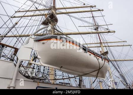 A white lifeboat on the side of a sea sailing ship. Life-saving equipment for seafarers during a deep-sea voyage Stock Photo