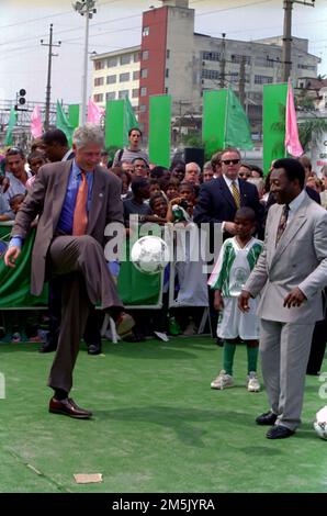 President William J. Clinton (left) kicking a soccer ball in front of Former Professional Soccer Player Pele Edises )far right) at Mangueira School in Rio De Janeiro, Brazil, 10/15/1997. Photo by Ralph Alswang, White House Collection. Stock Photo