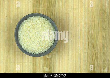 Rice in bowl on a straw background. Vegetarian organic product. Vintage view. Top view. Copy space. Stock Photo