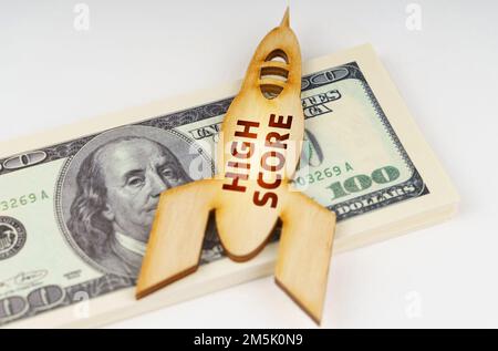 Business concept. On the dollars lies a wooden model of a rocket with the inscription - High Score. Image is partially blurred Stock Photo