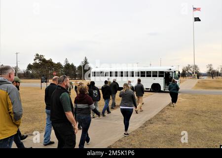 Participants in a Community Leader Engagement board a bus March 21, 2022, in front of Garrison Headquarters at Fort McCoy, Wis. More than a dozen community leaders from Tomah, Sparta, Black River Falls, La Crosse, and other nearby municipalities gathered at Fort McCoy to see the post’s mission first-hand. During their visit, the community leaders received a driving tour of the installation and made stops at the Combined Arms Collective Training Facility on South Post, Fort McCoy Commemorative Area, Fort McCoy Simulations Training Complex in the 200 block on the cantonment area, Garrison Headqu Stock Photo