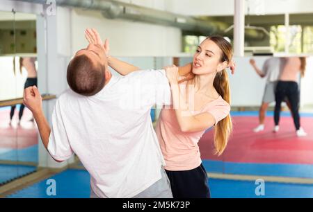 Active girl conducts painful grip on self-defense training in gym Stock Photo