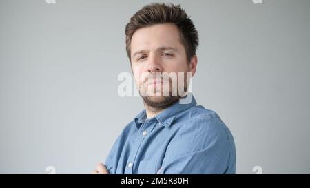 Young handsome man has serious expression poses in studio Stock Photo