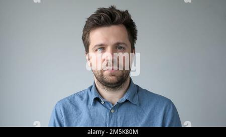 Young handsome man has serious expression poses in studio Stock Photo