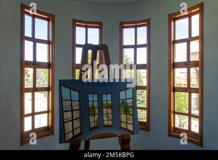 Double view. Window in a turret of the Casa de los Botines building by architect Antoni Gaudí with a painting of the same view. Stock Photo