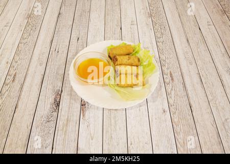 Small fried Thai spring rolls on a lettuce leaf and with dipping sauce Stock Photo