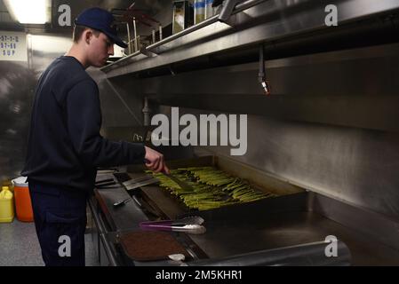 U.S. Coast Guard Petty Officer 2nd Class Christian Rocha, a Culinary Specialist aboard Coast Guard Cutter Spar, prepares the evening meal while underway in the St Lawrence River, March 22, 2022. Spar and her crew are traveling to Duluth, Minn. after a year-long maintenance period in Baltimore. Stock Photo