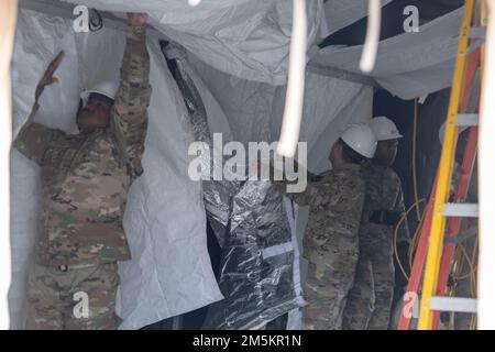 Chief Master Sgt. Jerry Dunn, left, 374th Airlift Wing command chief, and Airmen from the 117th Civil Engineer Squadron, Sumpter Smith Joint National Guard Base, Alabama, and the 908th CES, Maxwell Air Force Base, Alabama, begin to dismantle the former COVID-19 testing tent at Yokota Air Base, Japan, March 23, 2022. After 24 months of operation, new case numbers have finally dropped to a point where the 374th Medical Group can safely move its testing services back indoors. Stock Photo