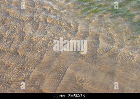 Clear, transparent, ripple ocean water over beach sand. Stock Photo