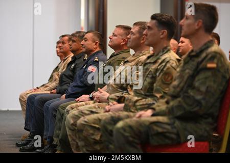 U.S. Air Force Col. Jason Gingrich, 39th Air Base Wing commander (center), U.S. Air Force Col. John Kelley, 39th Air Base Wing vice commander, and NATO allied commanders from Turkey Spain, Poland, and Hungary watch the Winds Aloft U.S. Air Forces in Europe Woodwind Quintet perform at Incirlik Air Base, Turkey, March 23, 2022. This reception served to celebrate the 70th anniversary of Turkey’s accession to NATO and foster interpersonal connections among Incirlik’s NATO commanders. Stock Photo