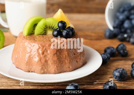 Plate with delicious chocolate pudding, blueberry, kiwi and lemon slices on wooden background Stock Photo