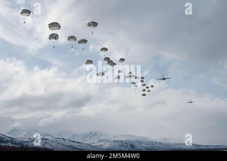 U.S. Army paratroopers assigned to the 4th Infantry Brigade Combat Team (Airborne), 25th Infantry Division, U.S. Army Alaska, jump from a U.S. Air Force C-17 Globemaster III over Malemute Drop Zone during airborne operations at Joint Base Elmendorf-Richardson, Alaska, March 24, 2022. The paratroopers conducted the training to strengthen mission readiness skills in an arctic environment. Stock Photo