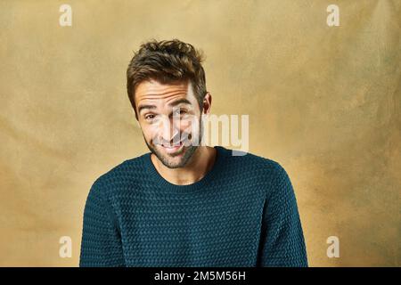 Handsome with a heart of gold. Studio shot of a handsome young man posing against a golden background. Stock Photo