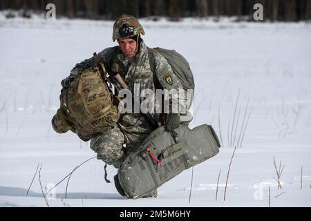 Army Spc. Anthony Gazzillo, a paratrooper assigned to the 3rd Battalion, 509th Parachute Infantry Regiment, 4th Infantry Brigade Combat Team (Airborne), 25th Infantry Division, U.S. Army Alaska, proceeds to the rally point after completing airborne training at Malemute Drop Zone, Joint Base Elmendorf-Richardson, Alaska, March 24, 2022. Army and Air Force units regularly train together to strengthen and maintain joint mission readiness skills in an arctic environment. Stock Photo