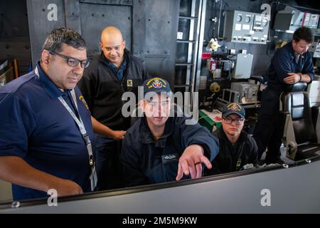 From left: Radar In-Service Engineering Agent Maximilian Lopez works with Operations Specialist Petty Officer 1st Class Elliot Cameron, Fire Controlman Petty Officer 1st Class Kyle Schoenthal and Sonar Technician Petty Officer 3rd Class Greylan Smith to troubleshoot computer systems in the Combat Information Center (CIC) on the bridge of USS Kansas City (LCS 22) during a recent Combat Systems Assessment Team (CSAT) event at Naval Surface Warfare Center, Port Hueneme Division. Homeported in San Diego, USS Kansas City is preparing for an upcoming deployment. Stock Photo