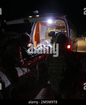 U.S. Army combat medics and other Coalition partners unload a mock patient from an ambulance during a mass casualty exercise March 24, 2022, at Al Asad Air Base, Iraq. The purpose of the Combined, Joint mass casualty exercise was to help participants hone their response skills to a mass casualty event and to build interoperability among Coalition partner forces. Stock Photo