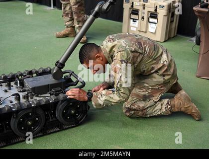 An explosive ordnance disposal technician uses a flashlight to inspect ...