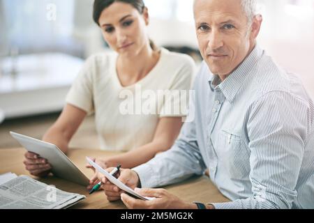 Collaborating to succeed. Portrait of two coworkers sitting at a table discussing paperwork. Stock Photo